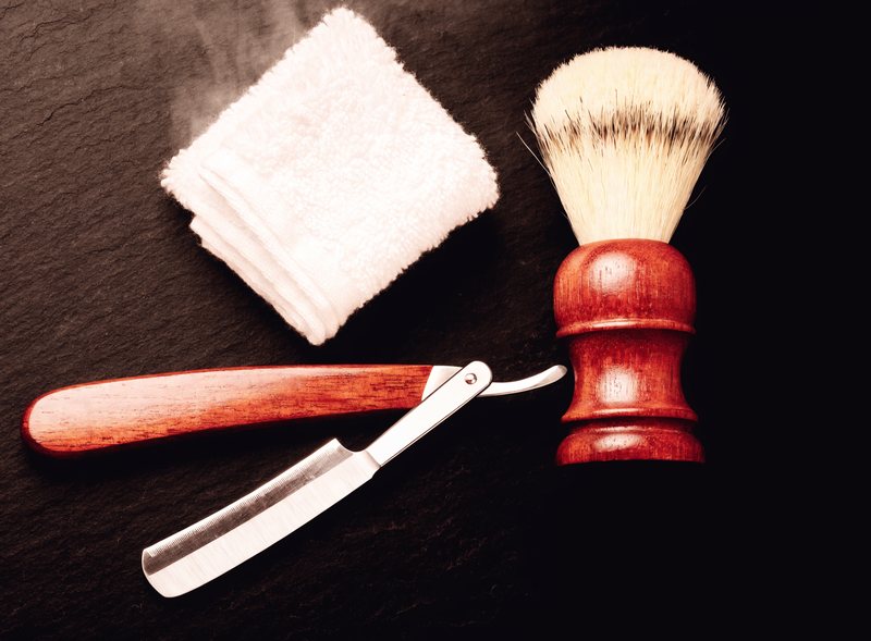 Straight razor, shaving brush and folded hot towel on slate